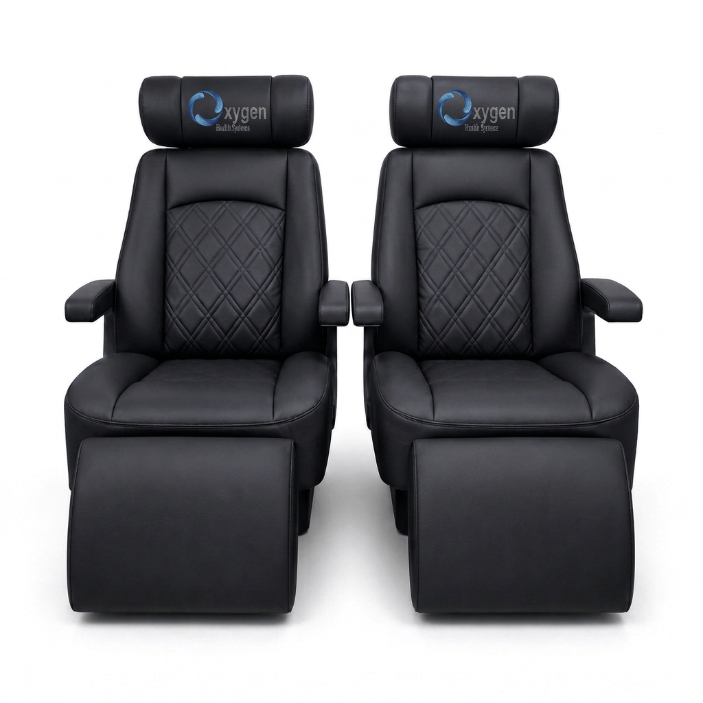 Two black quilted leather Oxygen Health Systems captain's chairs with diamond-stitched backrests, embroidered logo headrests, padded armrests, and extended footrests